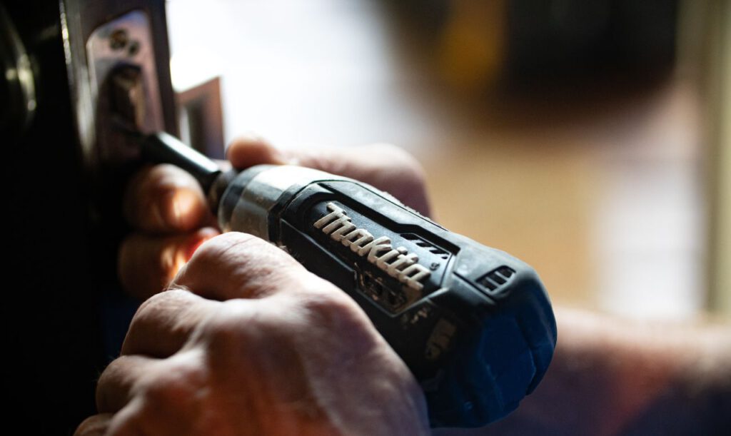 Ein Handwerker, der mit einem Akkuschrauber von Makita etwas befestigt.