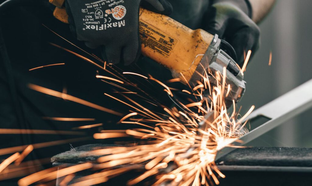 Ein Handwerker schleift mit einem Winkelschleifer Metall.