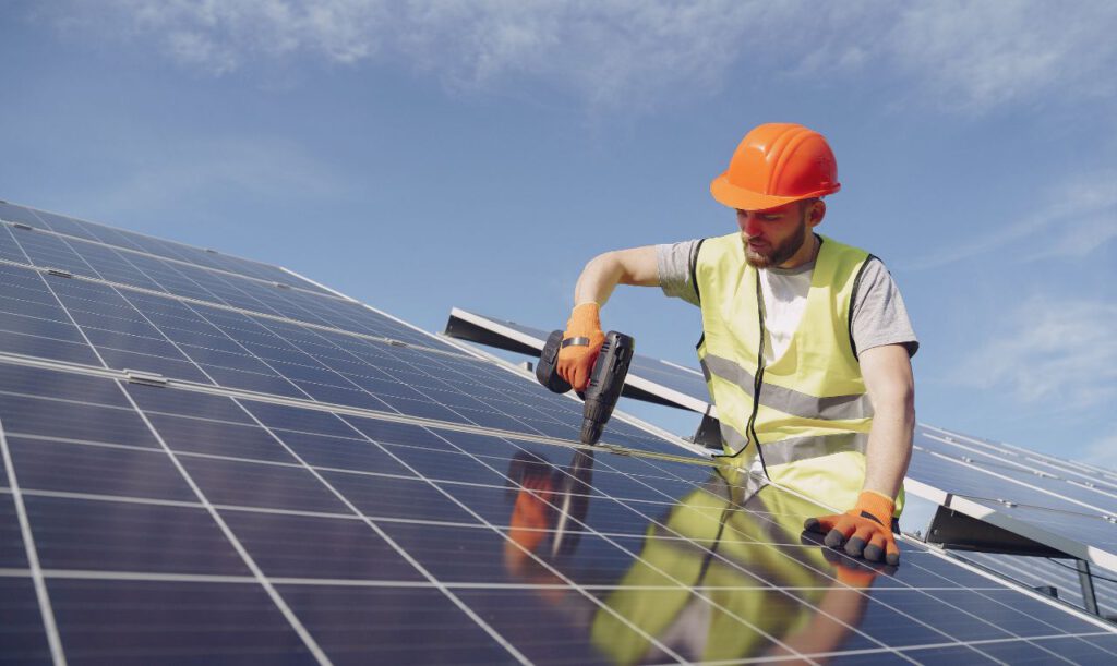 Ein Handwerker montiert eine PV-Anlage.