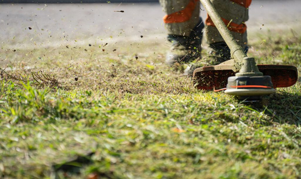 Ein Handwerker, der einen Garten senst.